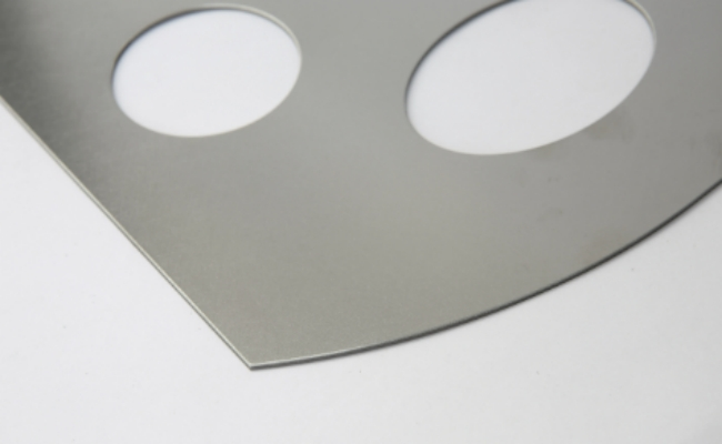 Close-up of a sheet metal part with two circular openings and a curved outer edge on a white background